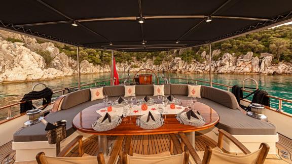 Elegant outdoor seating area with dining table, surrounding benches and beautiful views of the sea and rocks.